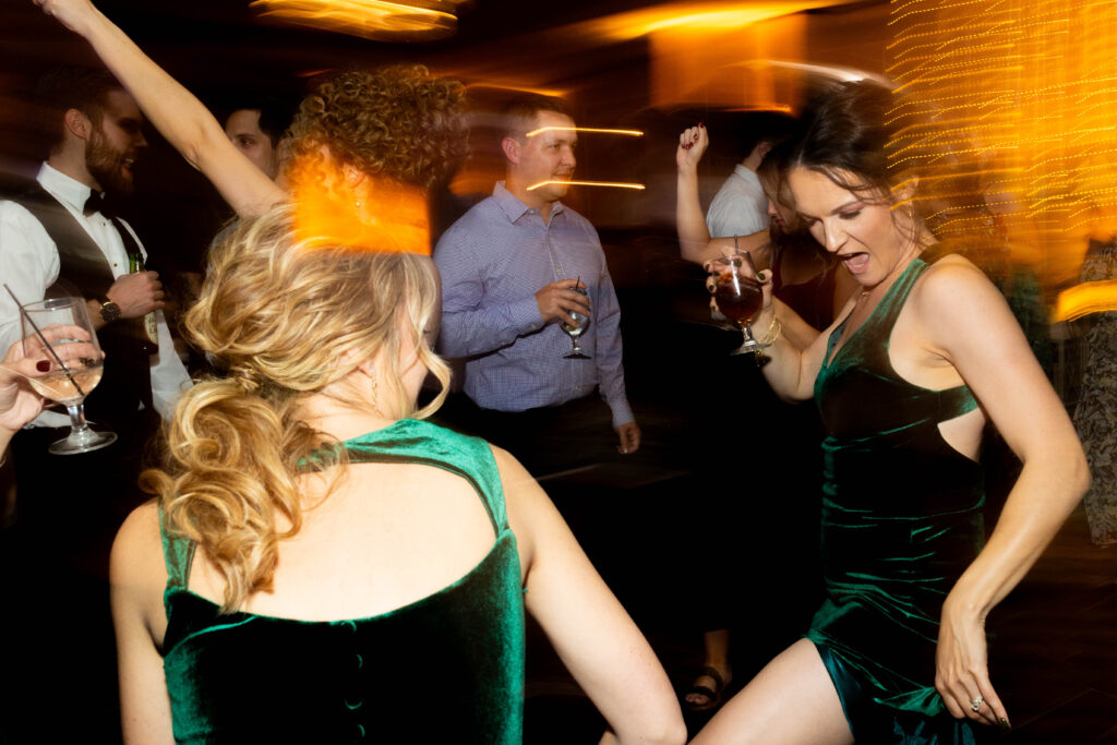 Image portraying wedding guests and bridesmaids having fun and dancing during wedding reception.