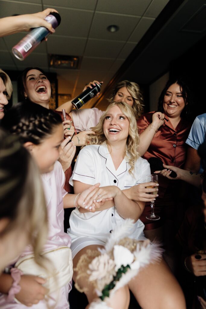 Fun and laughter are pictured in this image of bride and bridesmaids getting ready for wedding.